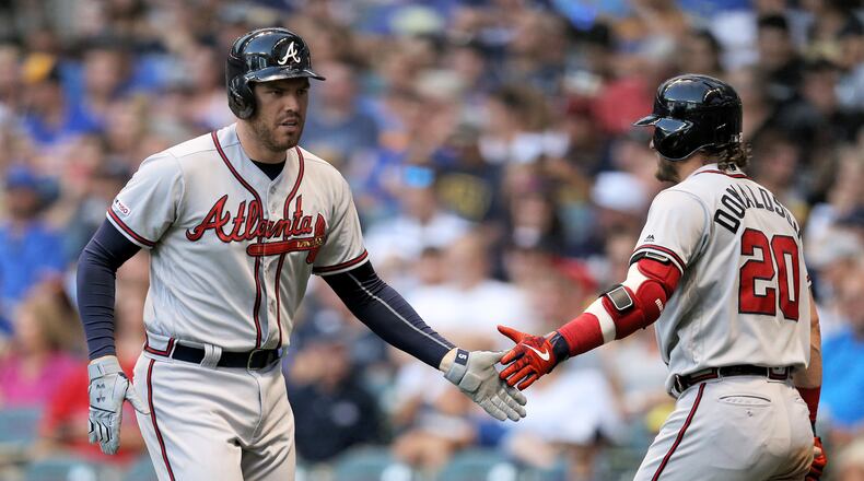 Braves' Freddie Freeman and Josh Donaldson celebrate after Freeman hit a home run in the fourth inning July 15, 2019, against the Brewers at Miller Park in Milwaukee.