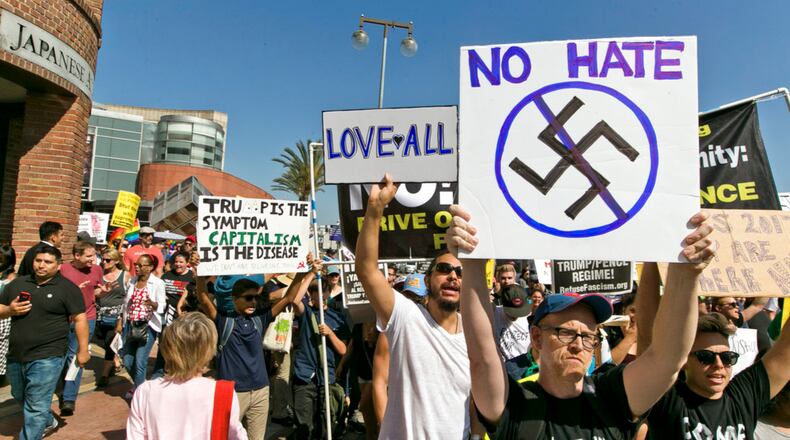 FILE--In this Aug. 13, 2017, file photo, demonstrators march in downtown Los Angeles decrying hatred and racism the day after a white supremacist rally that spiraled into violence in Charlottesville, Va. A monument at Hollywood Forever Cemetery commemorating Confederate veterans has been taken down after hundreds of people demanded its removal. (AP Photo/Damian Dovarganes, file)