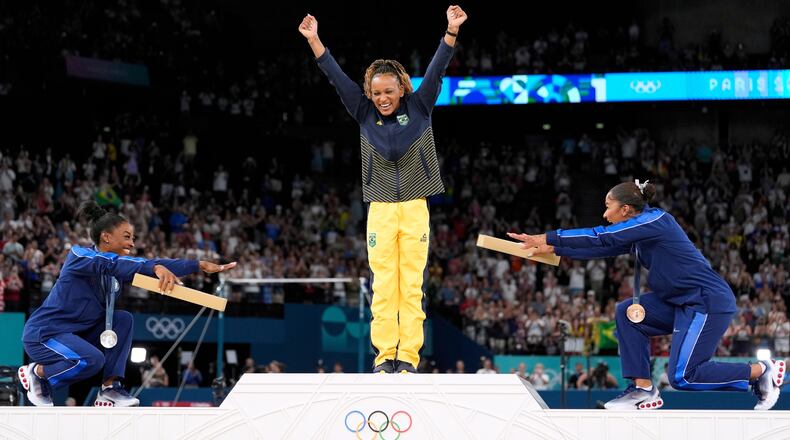 FILE - Silver medalist Simone Biles, of the United States, left, and bronze medalist Jordan Chiles, of the United States, right, bow to gold medalist Rebeca Andrade, of Brazil, during the medal ceremony for the women's artistic gymnastics individual floor finals at Bercy Arena at the 2024 Summer Olympics, Aug. 5, 2024, in Paris, France. (AP Photo/Abbie Parr, File)