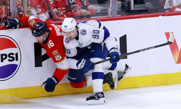 Tampa Bay Lightning defenseman J.J. Moser (90) checks Florida Panthers center Aleksander Barkov (16) into the boards during the first period in Game 3 of an NHL hockey Stanley Cup first-round playoff series, Saturday, April 26, 2025, in Sunrise, Fla. (AP Photo/Rhona Wise)