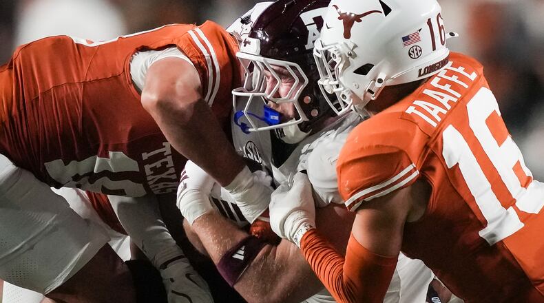 Texas defensive back Warren Roberson (24) and linebacker Liona Lefau (18) bring down Texas A&M tight end Theo Melin Öhrström (17) during the second quarter of an NCAA college football game against Texas A&M in Austin, Texas, Friday, Nov. 28, 2025. (Sara Diggins/Austin American-Statesman via AP)