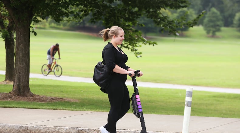 A woman rides a scooter by Piedmont Park in Atlanta on Wednesday, July 18, 2019. (Christina Matacotta/Christina.Matacotta@ajc.com)