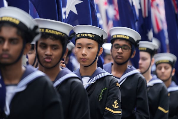 Cadets carrying Australian flags march past thousands of people lining the street to pay tribute to their war dead during the Anzac Day parade in Sydney, Australia, Friday, April 25, 2025. (AP Photo/Rick Rycroft)