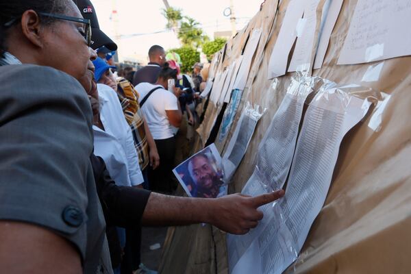 People searching for their missing relatives peruse a list of names outside the Jet Set nightclub after its roof collapsed during a merengue concert in Santo Domingo, Dominican Republic, Tuesday, April 8, 2025. (AP Photo/Ricardo Hernandez)