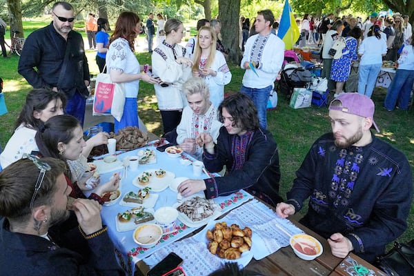Eurovision competitor band Ziferblat from Ukraine eats traditional food during a family meeting of Ukrainian people in a park in Basel as part of the 69th Eurovision Song Contest week, in Basel, Switzerland, Thursday, May 15, 2025. (AP Photo/Martin Meissner)