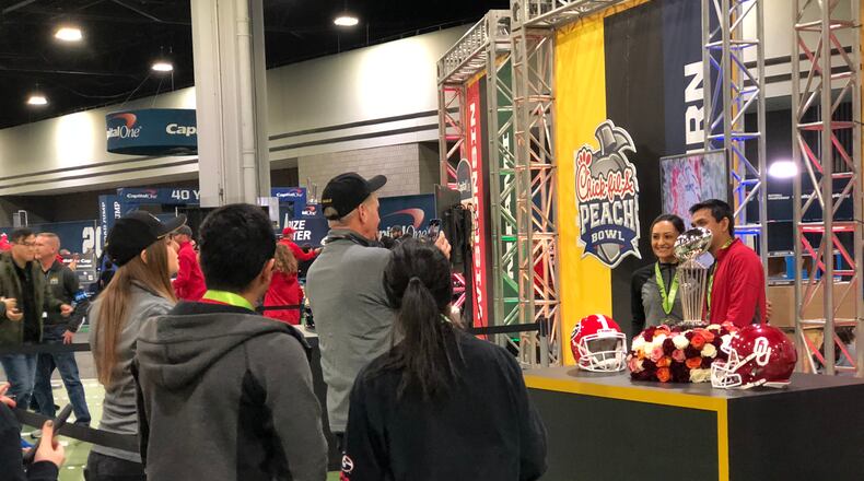 Georgia Bulldogs fans take pictures with the Rose Bowl trophy during the Georgia World Congress Center’s Fan Central festival during the College Football Playoff National Championship weekend. LEON STAFFORD/AJC