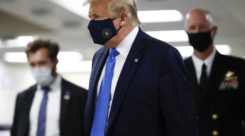 President Donald Trump wears a mask Saturday as he walks down the hallway during his visit to Walter Reed National Military Medical Center in Bethesda, Md. (AP Photo/Patrick Semansky)
