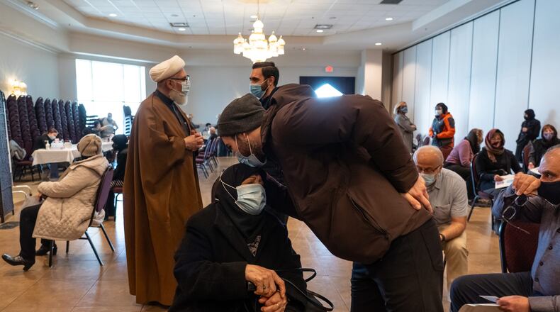 State Rep. Abdullah Hammoud, center, of Dearborn kisses his 83-year-old grandmother Fatima Hammoud of Dearborn Heights after she received her first round of the Pfizer COVID-19 vaccine as his uncle Islamic Center of America Imam Sheikh Ahmad Hammoud, left, speaks to another man during a vaccination clinic as part of an outreach initiative by Henry Ford Health System at the Islamic Center of America in Dearborn on Monday, March 8, 2021. (Ryan Garza/Detroit Free Press/TNS)