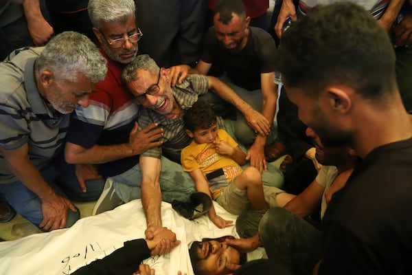 Ata Qasas, center, mourns over the body of his son Rashad Qasas, who was killed while heading to an aid distribution hub, during his funeral in Rafah, southern Gaza Strip, Wednesday, June 11, 2025. (AP Photo/Mariam Dagga)