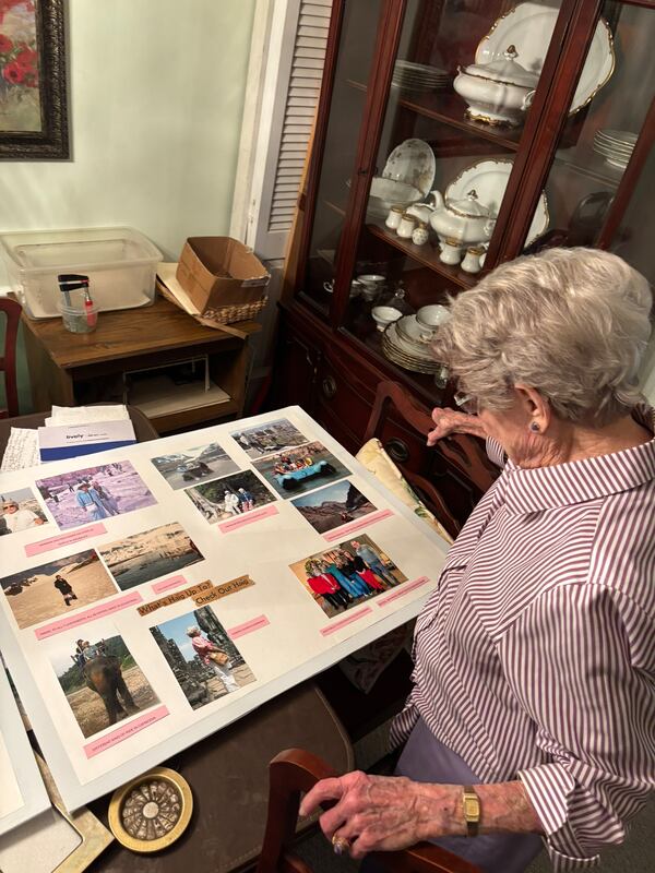 Barbara Haig, 100, looks over poster boards full of photographs that she said show some of her trips to 50 states, seven continents and 75 countries. (Doug Turnbull for the AJC)
