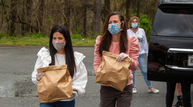Compassion Kitchen Project co-founders Isabel Rice (left) and Lisa Blanco carry Easter meals for families in need at The Mission church in Atlanta on Thursday March 25th, 2021. PHIL SKINNER FOR THE ATLANTA JOURNAL-CONSTITUTION.