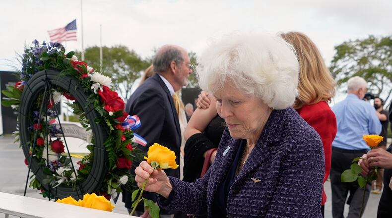 Jane Smith-Wolcott, center, widow of Challenger pilot Michael Smith puts a flower on a memorial during NASA's Day of Remembrance for the 40th Anniversary of the Challenger tragedy at the Kennedy Space Center Visitor Complex in Cape Canaveral, Fla., Thursday, Jan. 22, 2026. (AP Photo/John Raoux)