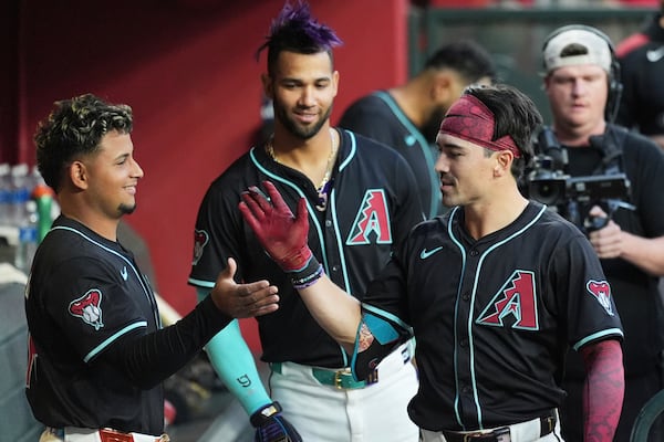 Arizona Diamondbacks' Corbin Carroll, right, celebrates his home run against the Tampa Bay Rays with Diamondbacks' Gabriel Moreno, left, as Diamondbacks' Lourdes Gurriel Jr., center, looks on during the first inning of a baseball game Wednesday, April 23, 2025, in Phoenix. (AP Photo/Ross D. Franklin)