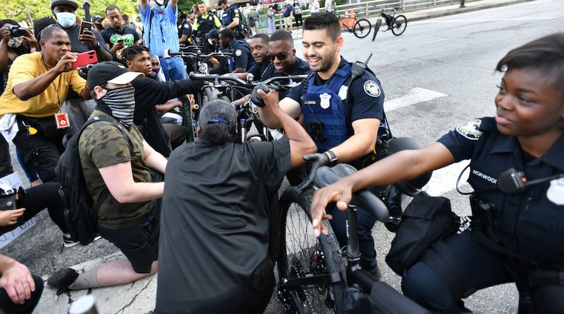 Atlanta Police Officer J. Nguyen (center) and his fellow cops knee-down in a symbolic gesture of solidarity with demonstrators, and exchange handshakes and fist bumps with protesters at Centennial Olympic Park on June 3, 2020 — the sixth consecutive day of protests in Atlanta against police brutality and racism. (Hyosub Shin / Hyosub.Shin@ajc.com)