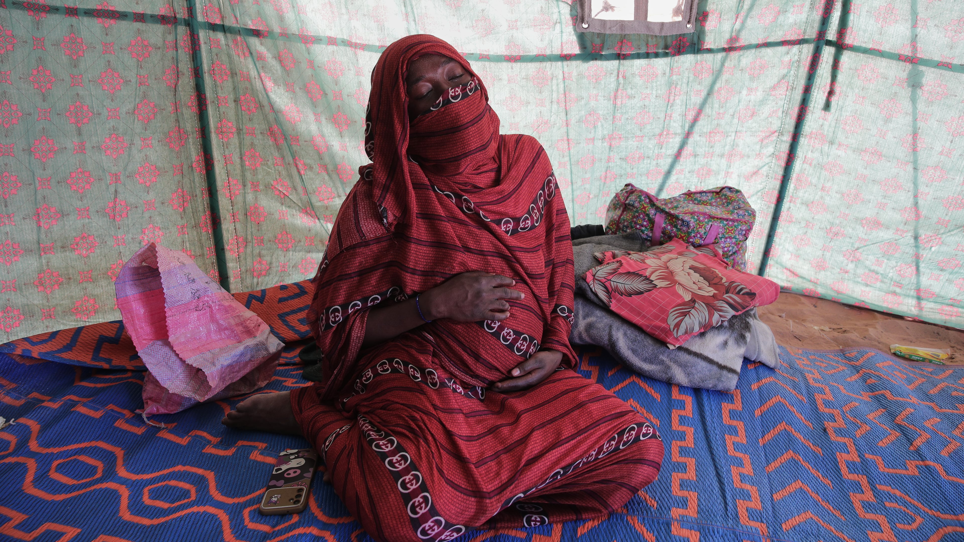 Nadra Mohamed Ahmed, 21, reacts during an interview with The Associated Press inside her tent at the newly established El-Afadh camp in Al Dabbah, Sudan's northern state, Monday, Nov. 17, 2025. (AP Photo/Marwan Ali)