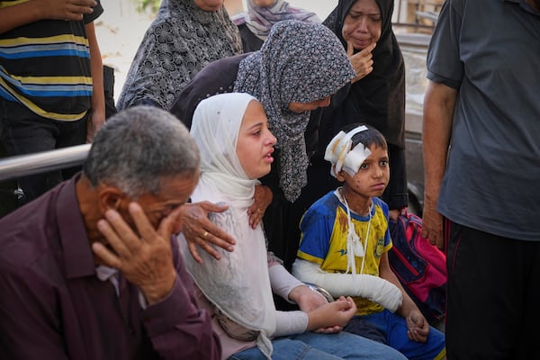 Hamam Al-Farani sits next to his sister, in white, along with other family members as the body of their father Alaa, killed in an Israeli army strike that also injured the boy, is prepared for burial at Shifa hospital in Gaza City, on Tuesday, June 24, 2025. (AP Photo/Jehad Alshrafi)