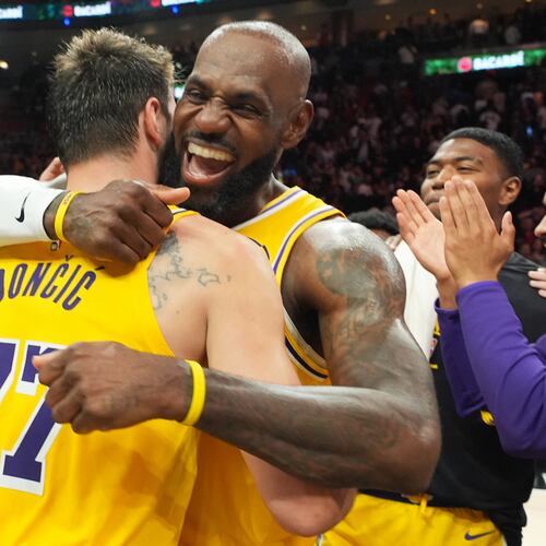Los Angeles Lakers guard Luka Doncic (77) and forward LeBron James, right, embrace after defeating the Miami Heat in an NBA basketball game, Thursday, March 19, 2026, in Miami. (AP Photo/Lynne Sladky)