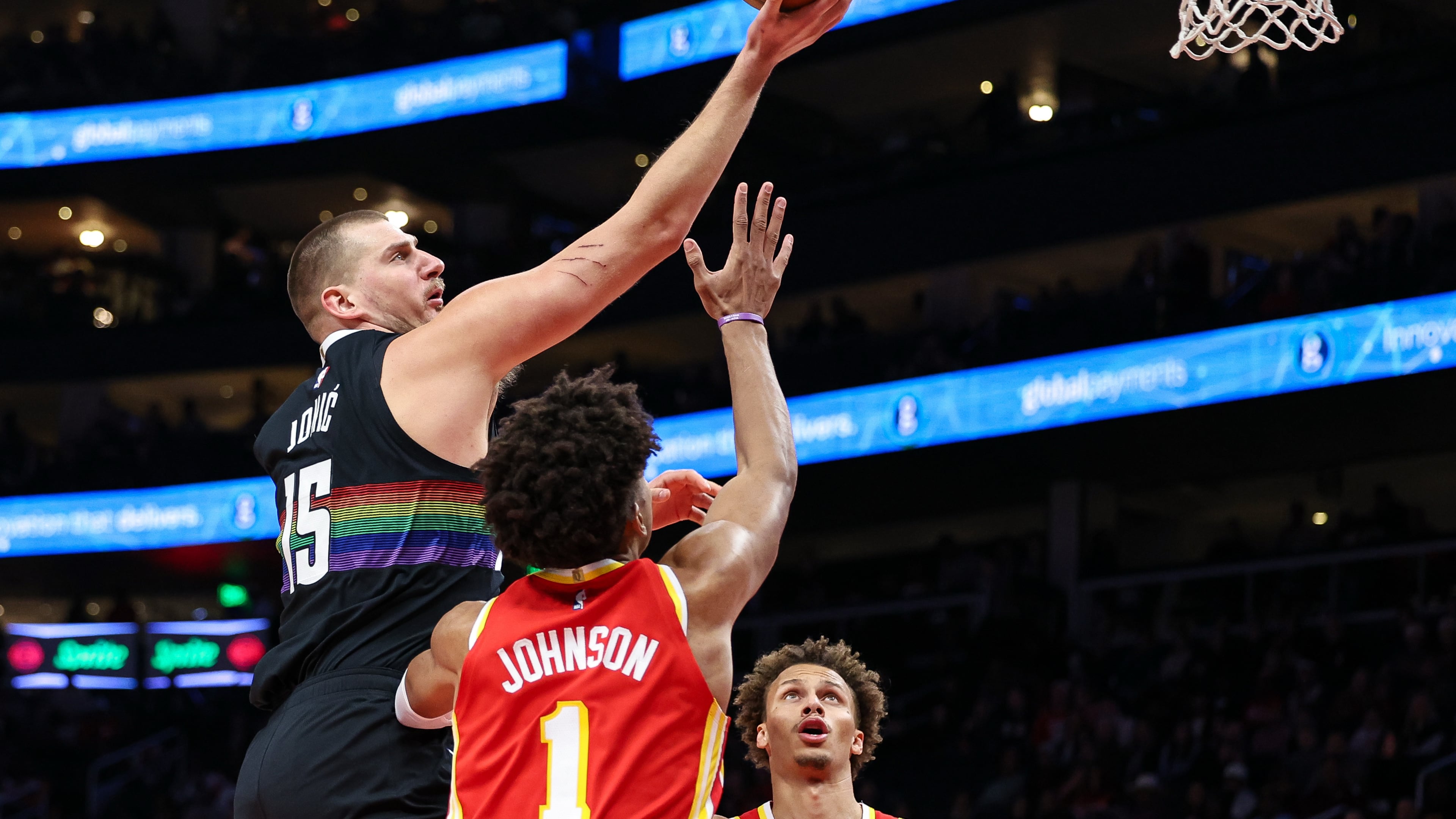 Denver Nuggets center Nikola Jokic, left, shoots the ball over Atlanta Hawks forward Jalen Johnson (1) during the first half of an NBA basketball game, Friday, Dec. 5, 2025, in Atlanta. (AP Photo/Colin Hubbard)