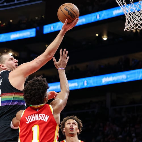 Denver Nuggets center Nikola Jokic, left, shoots the ball over Atlanta Hawks forward Jalen Johnson (1) during the first half of an NBA basketball game, Friday, Dec. 5, 2025, in Atlanta. (AP Photo/Colin Hubbard)
