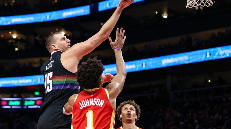 Denver Nuggets center Nikola Jokic, left, shoots the ball over Atlanta Hawks forward Jalen Johnson (1) during the first half of an NBA basketball game, Friday, Dec. 5, 2025, in Atlanta. (AP Photo/Colin Hubbard)