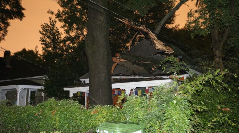 A tree rests on top of a house on Bryan Street in Grant Park after storms rolled through metro Atlanta on Thursday evening August 7, 2014. BEN GRAY / BGRAY@AJC.COM