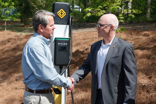 (Left to right) Gov. Brian Kemp shakes hands with Rivian Chief Legal Officer Michael Callahan after unveiling the first ever Rivian charging station at Tallulah Gorge State Park on Thursday, April 20, 2023.  (Natrice Miller/natrice.miller@ajc.com)