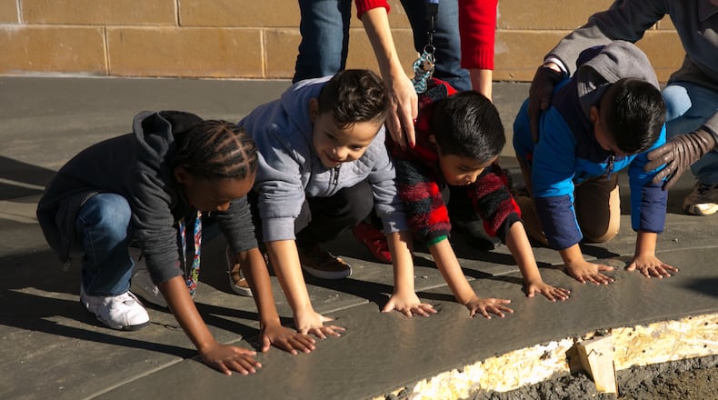 Children from Peachtree Elementary in Peachtree Corners born in 2012 put their hand prints in wet cement at a large circular concrete area at the Peachtree Corners Town Center. PHOTO / JASON GETZ