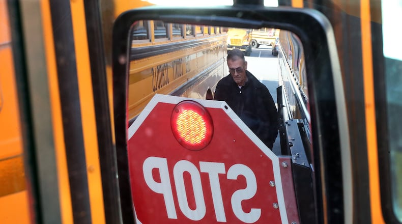 Fleet manager Charles Smith is reflected in a side mirror while going over a detecting system that can warn drivers there is an object near their bus at the Carroll Pitts Jr. Transportation Center in Marietta. Attention to school bus safety has heightened after students were killed in a Chattanooga bus crash. Curtis Compton/ccompton@ajc.com