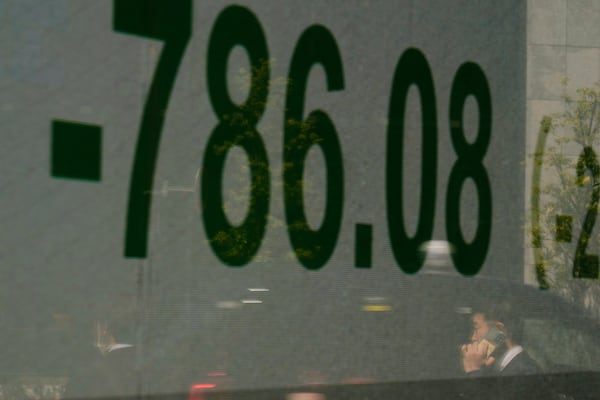 A man talking on the phone is reflected on a screen showing Japan's Nikkei 225 index at a securities firm in Tokyo, Wednesday, April 9, 2025. (AP Photo/Hiro Komae)