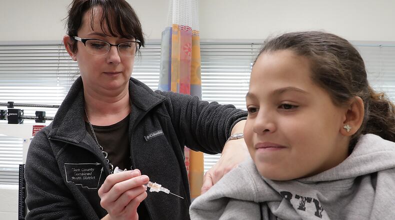 Kristen Earley, an RN at the Clark County Combined Health District, gives Braylinne Muhammad, 11, a flu shot Friday in the District’s offices. BILL LACKEY/STAFF