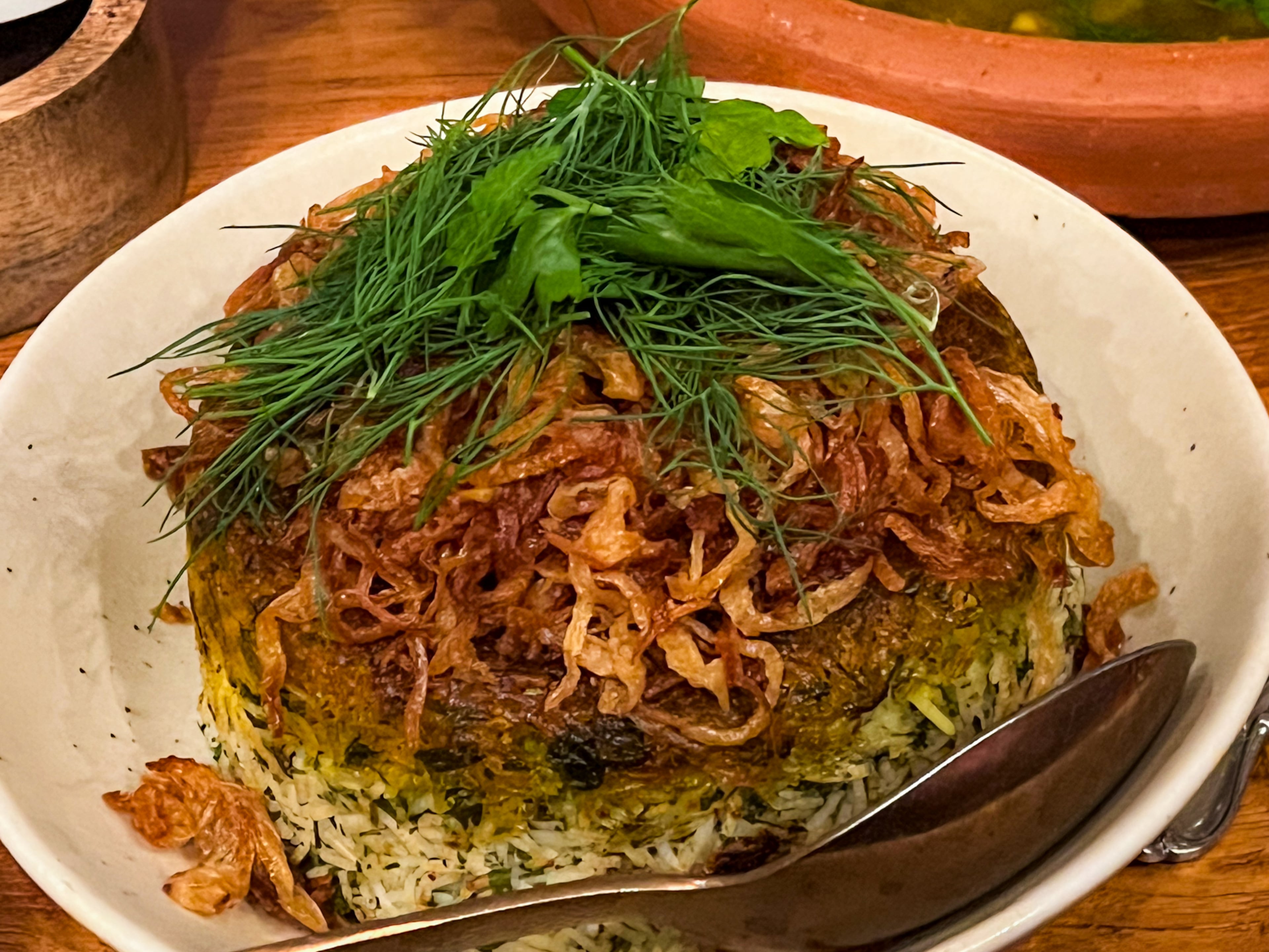 One of Delbar's Persian-style rice dishes, sabzi polo, is cooked until crispy on the bottom and served with fried scallions and fresh herbs. (Henri Hollis/AJC 2023)
