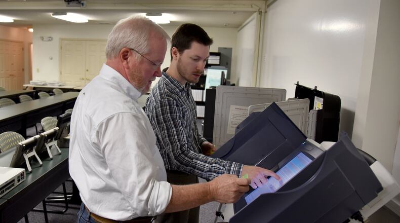 Merle King (left), the executive director of the Center for Election Systems at Kennesaw State University, and Steven Dean, the technical coordinator, review the setup procedure of a voting machine. The center outsources repairs to Georgia’s 27,000 voting machines but is responsible to testing each unit before it is put back into service. BRANT SANDERLIN/BSANDERLIN@AJC.COM
