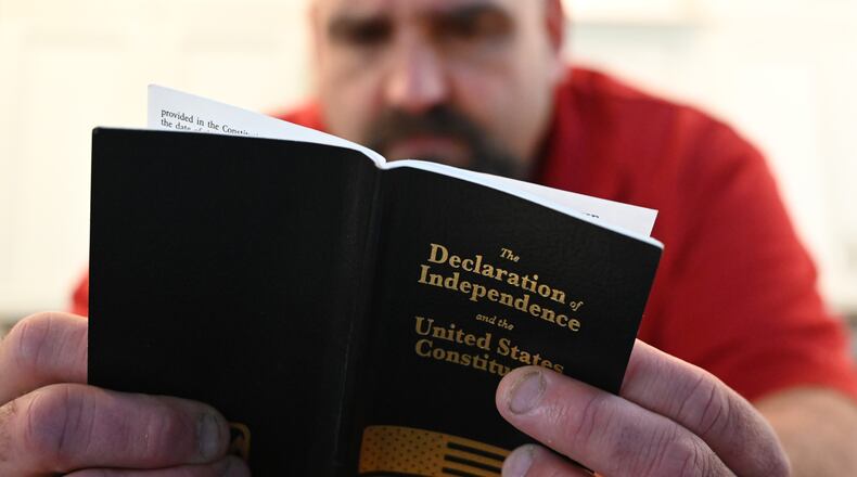 Phillip "Bunky" Crawford looks at a pocket-size copy of The Declaration of Independence and the United States Constitution at his home on Thursday, Dec. 19, 2024, in Bremen. Crawford is a Jan. 6 defendant who is awaiting sentencing on charges that he assaulted police on Jan. 6, 2021. (Hyosub Shin/AJC)