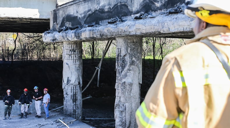 Officials survey the damage Friday caused by the collapse of a portion of the northbound lanes of I-85 in Buckhead following a massive fire during Thursday's evening rush hour.