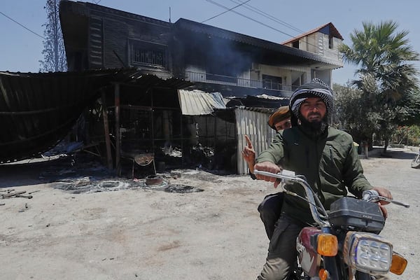 Syrian government soldiers drive in front of a house that was burned during the clashes between the Syrian government forces and Druze militias on the outskirts of Sweida city, southern Syria, Wednesday, July 16, 2025. (AP Photo/Omar Sanadiki)