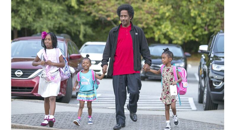 William White IV walks his daughters Allison White (from left), Amber White (second from left) and Ashley White (right) to M. Agnes Jones Elementary School, Atlanta. Milton has awarded a contract to create a smartphone app that would encourage kids to walk to school. AJC FILE / ALYSSA POINTER / ALYSSA.POINTER@AJC.COM