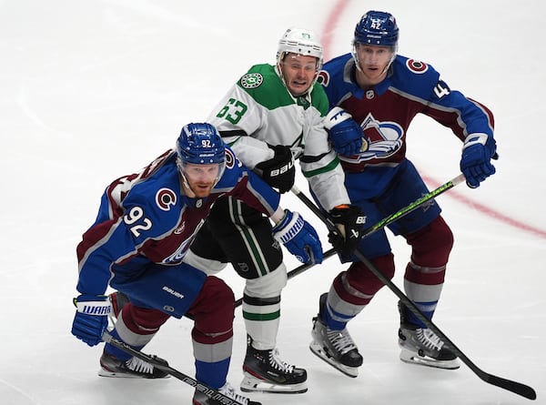 Dallas Stars right wing Evgenii Dadonov, center, is sandwiched between Colorado Avalanche left wing Gabriel Landeskog, left, and defenseman Josh Manson in the third period of Game 4 of an NHL hockey first-round playoff series Saturday, April 26, 2025, in Denver. (AP Photo/David Zalubowski)