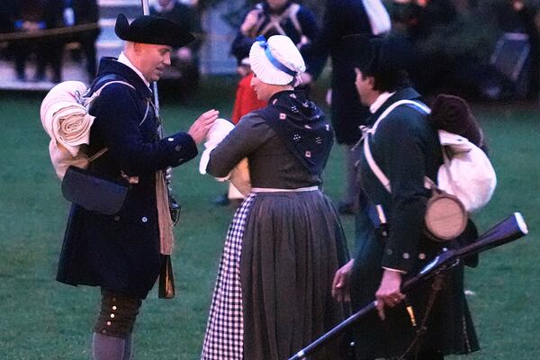 A New England colonial militia man, also known as a Minuteman, caresses the head of a baby prior to facing the British Regulars during a reenactment celebration of the 250th anniversary of the Battle of Lexington and start of the American Revolution, Saturday, April 19, 2025, in Lexington, Mass. (AP Photo/Charles Krupa)