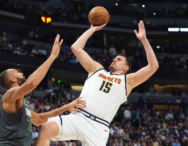 Denver Nuggets center Nikola Jokic, right, shoots for a basket over Minnesota Timberwolves center Rudy Gobert in the first half of an NBA basketball game Tuesday, April 1, 2025, in Denver. (AP Photo/David Zalubowski)