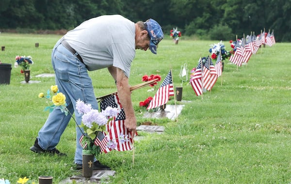 Retired Navy veteran Randy Melton places American flags at the gravesites of veterans in the Field of Honor on Tuesday in preparation for the Memorial Day weekend at Owensboro Memorial Gardens in Owensboro, Ky., on May 20, 2025. Melton is a member of all of the veterans organizations in town and volunteers every year to place the flags. (Alan Warren/The Messenger-Inquirer via AP)