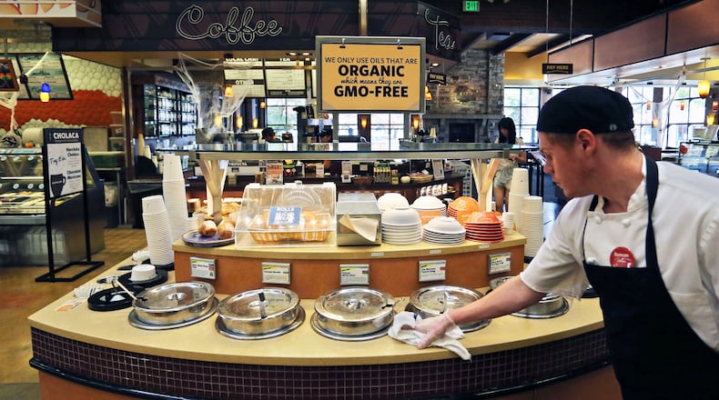 FILE - In this Oct. 23, 2014 file photo, a grocery store employee wipes down a soup bar with a display informing customers of organic, GMO-free oils, in Boulder, Colo. (AP Photo/Brennan Linsley, File)