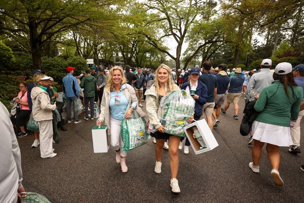 Michele Peel and Morgan Anton, both of Augusta, carry their recent purchases at the Golf Shop near the first fairway during a practice round at the Masters golf tournament, Monday, April 7, 2025, in Augusta, Ga. (Jason Getz / AJC)