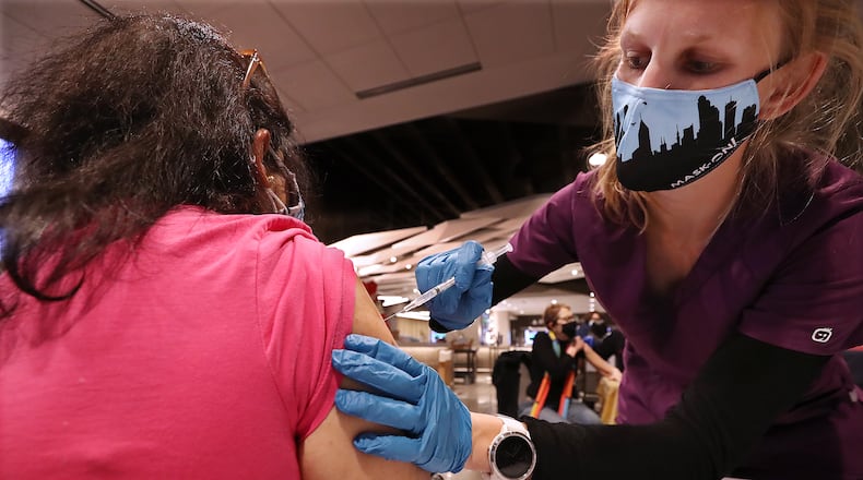 Veena Kalale gets a Pfizer vaccine shot from Fulton County Board of Health registered nurse Greer Pearson at the mass vaccination site at Mercedes-Benz Stadium last week. (Curtis Compton / Curtis.Compton@ajc.com)
