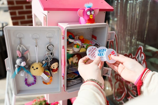 Mallory Gay, one of the co-owners of the Sincerely Yours bookstore in Smyrna, prepares to add stickers to their new trinket box attached to a small library bookstore box at their establishment on Wednesday, April 29, 2026.  (Miguel Martinez/AJC)