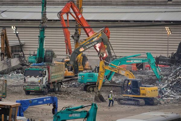 A rescuer walks past earth-movers clearing the debris of an under-construction high-rise building that collapsed after an earthquake in Bangkok, Thailand, Monday, March, 31, 2025. (AP Photo/Manish Swarup)