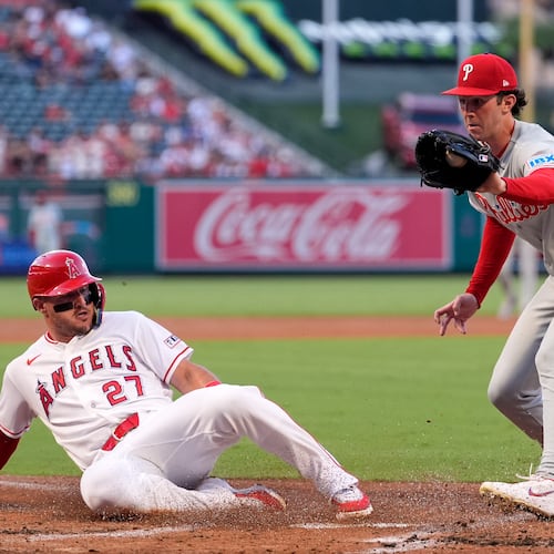 Los Angeles Angels' Mike Trout, left, scores on wild pitch by Philadelphia Phillies starting pitcher Andrew Painter, left, as Painter takes a late throw during the first inning of a baseball game Friday, Aug. 28, 2026, in Anaheim, Calif. (AP Photo/Mark J. Terrill)