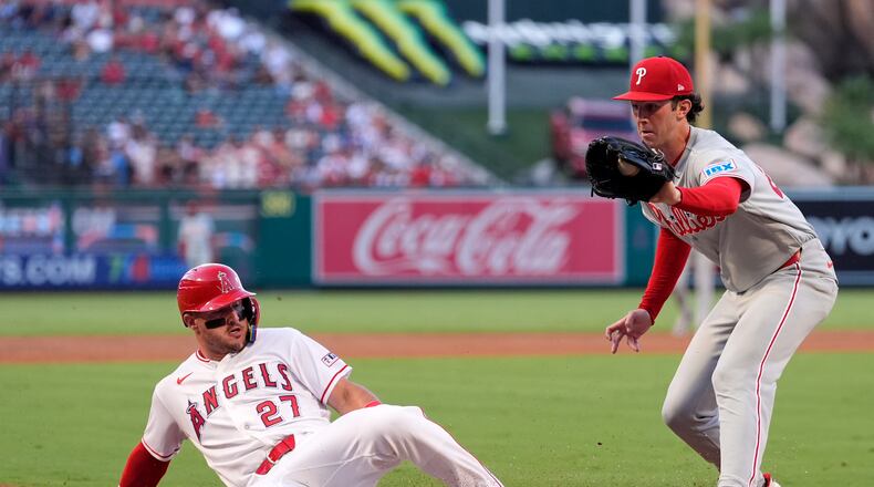 Los Angeles Angels' Mike Trout, left, scores on wild pitch by Philadelphia Phillies starting pitcher Andrew Painter, left, as Painter takes a late throw during the first inning of a baseball game Friday, Aug. 28, 2026, in Anaheim, Calif. (AP Photo/Mark J. Terrill)