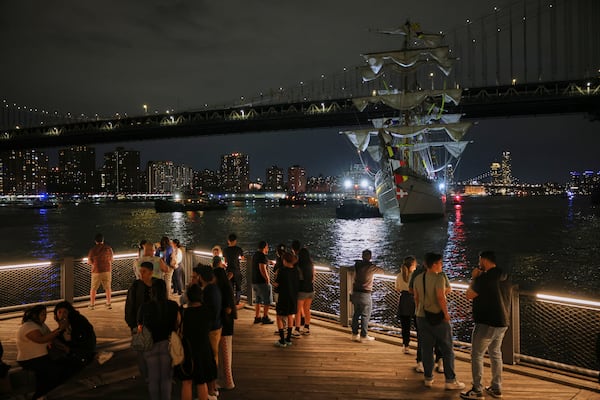 Visitors to Brooklyn Bridge Park look on as a masted Mexican Navy training ship sits stranded near the Manhattan Bridge after colliding with the Brooklyn Bridge, Saturday, May 17, 2025, in New York. (AP Photo/Yuki Iwamura)