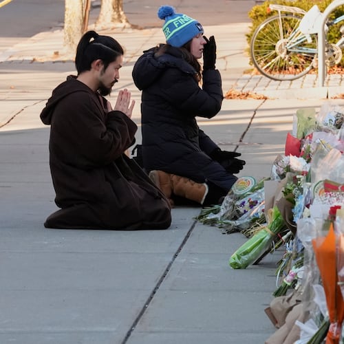 Visitors kneel at a makeshift memorial for the shooting victims outside the Engineering Research Center at Brown University, Tuesday, Dec. 16, 2025, in Providence, R.I.(AP Photo/Robert F. Bukaty)