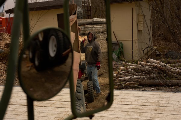 Morris Demoski tosses a split log into the back of a dump truck Thursday, May 22, 2025, in Galena, Alaska. (AP Photo/John Locher)
